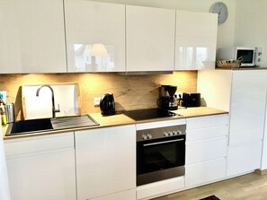 Eine moderne Küche mit Einbauofen, Kaffeemaschine und Mikrowelle.