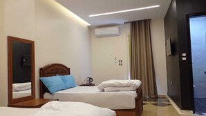 Habitación de hotel con dos camas, un espejo, cafetera y televisión.