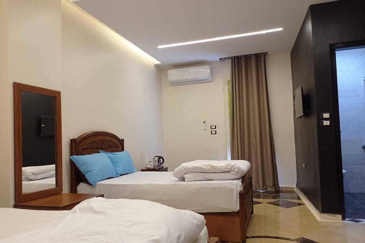 A hotel room with two beds, a mirror, a coffee maker, and a TV.