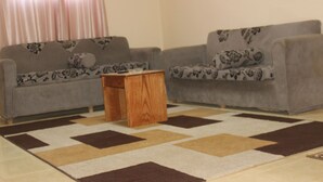 Una sala de estar con dos sofás grises de tapicería floral, una mesa de centro de madera y una alfombra estampada.