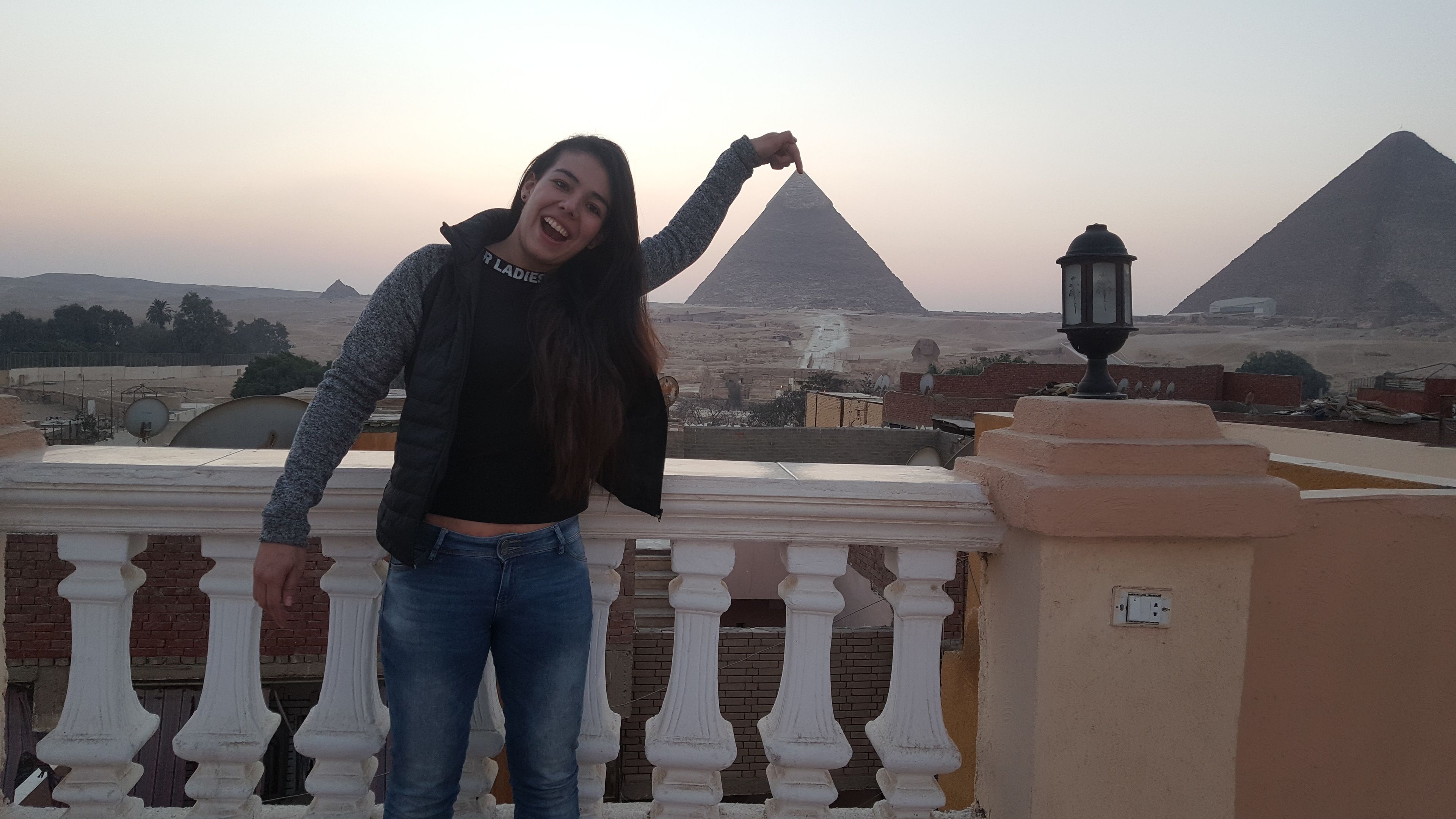 A person standing on a balcony overlooking pyramids.