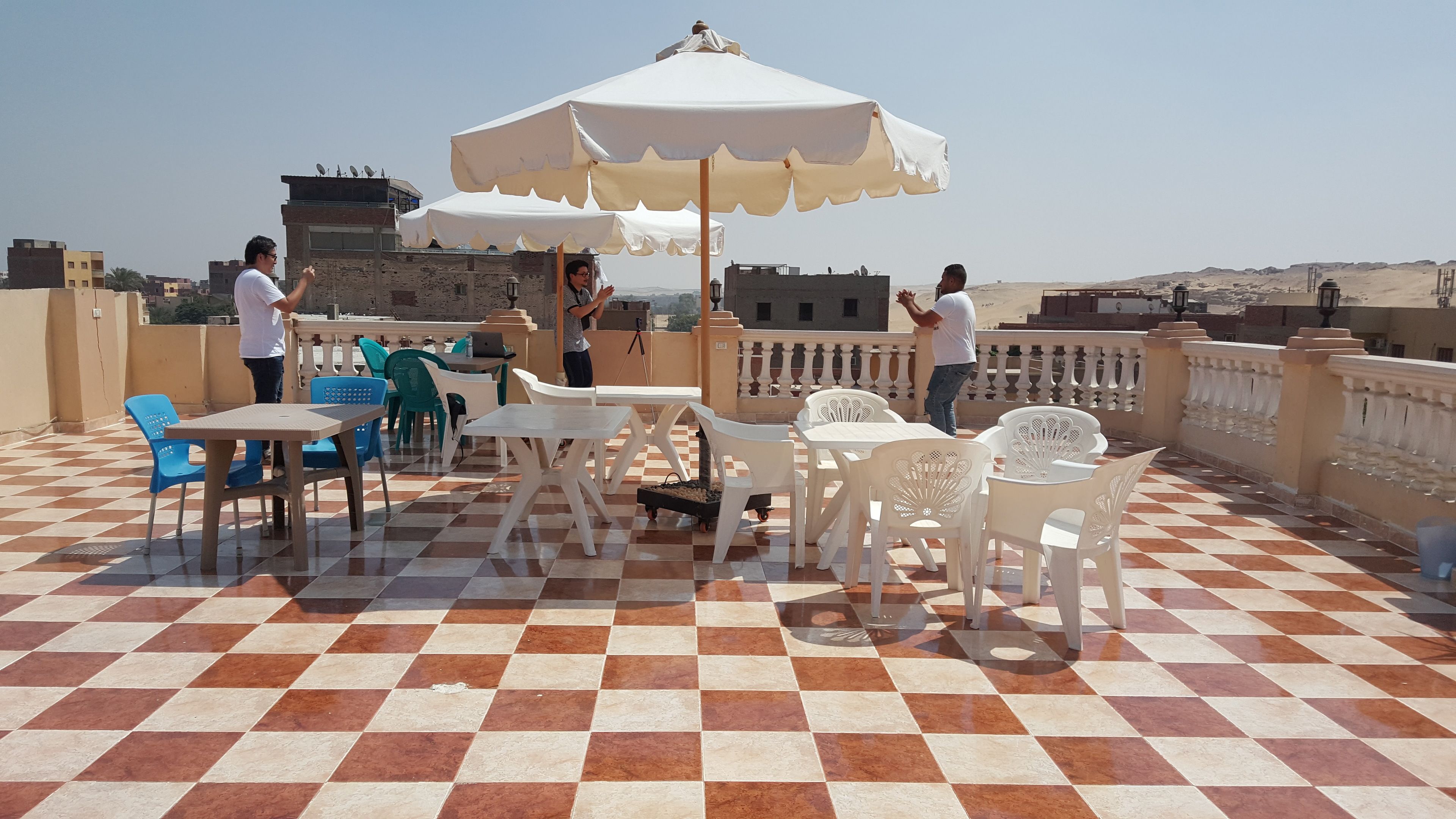 A rooftop terrace with checkered flooring, outdoor seating, and umbrellas.