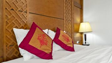 A neatly made bed with white sheets and two decorative pillows with a geometric pattern.