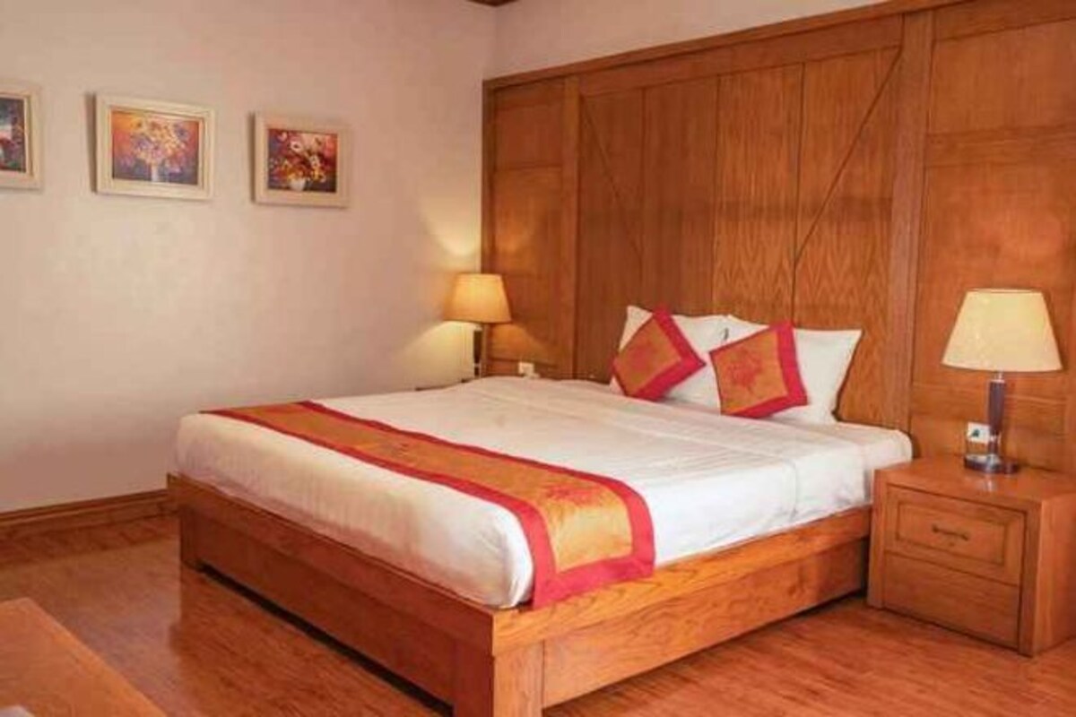 Een hotelkamer met een houten bed, twee nachtkastjes met lampen, en een houten hoofdeinde.
