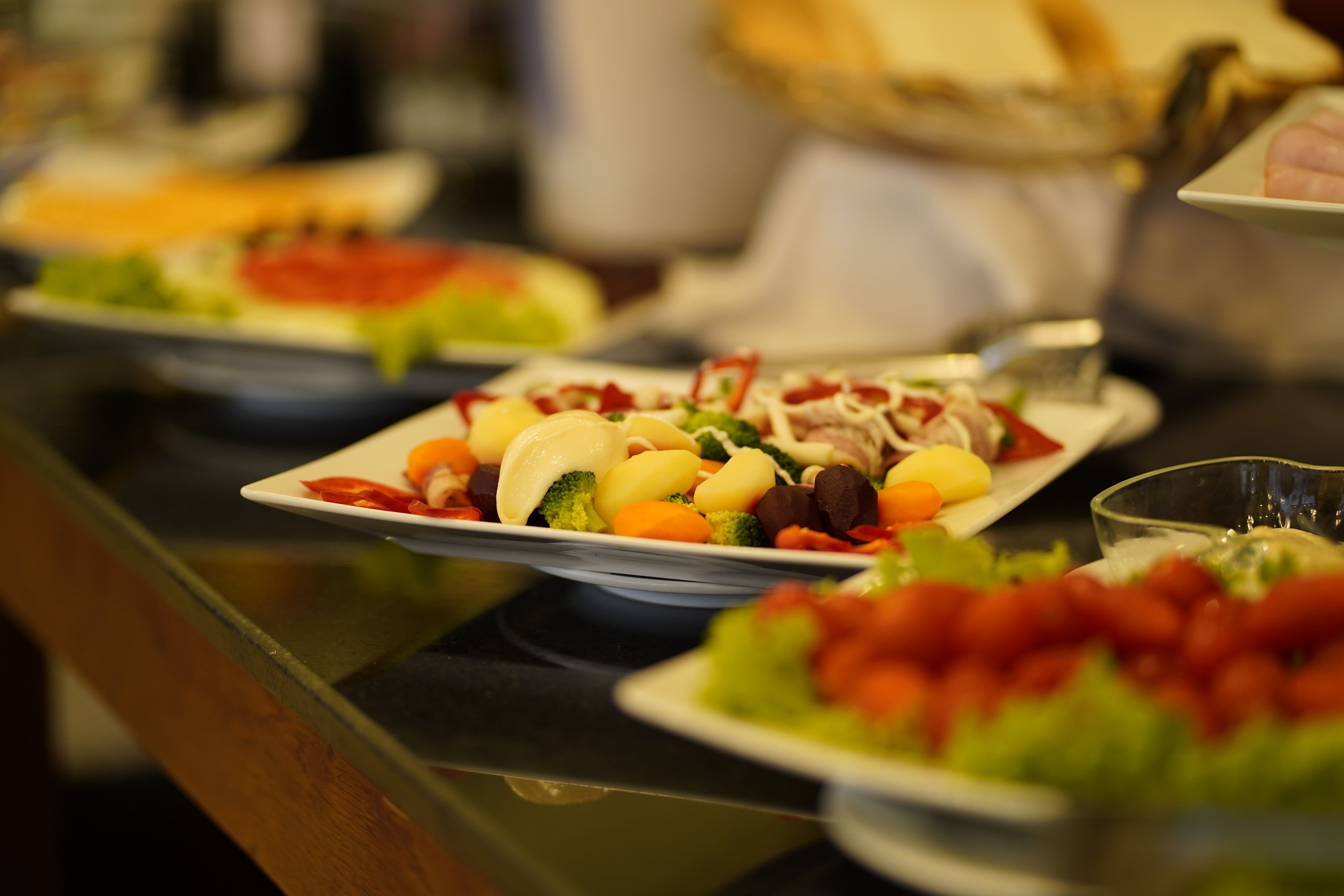 Una mesa de buffet con diversos platos, incluyendo ensaladas, verduras y carnes.