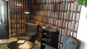 A modern living room with a bookshelf, two armchairs, a coffee table, and a patterned rug. - Hôtel Le Dauphin (Saint-Denis-de-l'Hôtel)