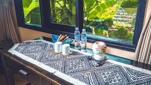 A table with a patterned tablecloth, two white mugs, two water bottles, and a decorative item. - Mai Chau Sunrise Village (Mai Chau)