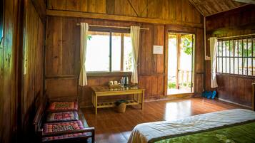 A wooden room with a bed, a table with items, a bench, and a door leading outside.