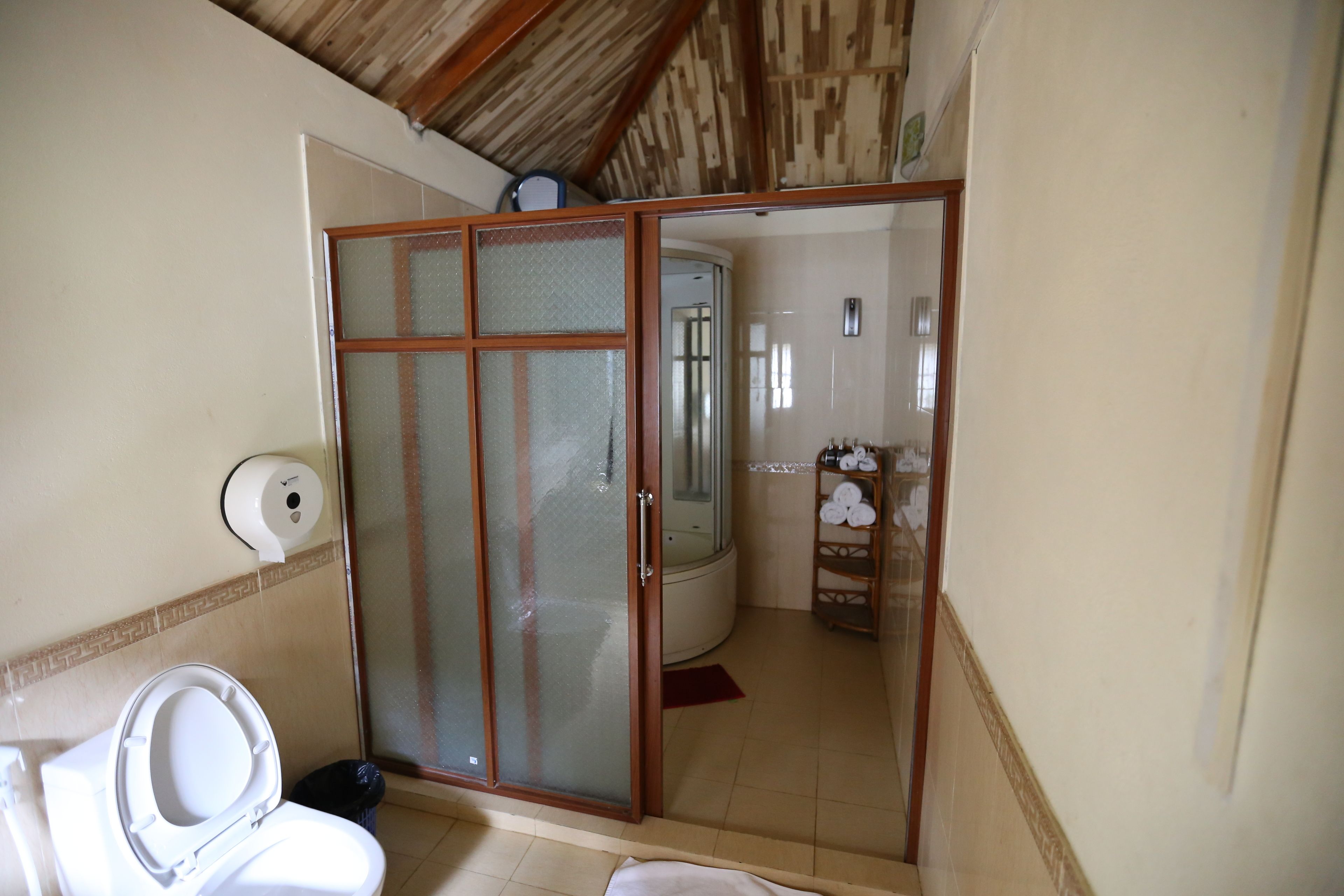 Un baño con inodoro, ducha y cabina de ducha con mampara de vidrio.