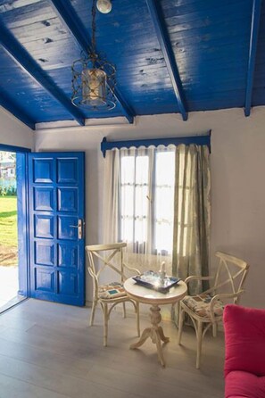 A room with a blue door, a table with chairs, and a hanging light fixture. - Mavi Zeytin Butik Hotel (Seferihisar)