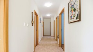Ein Korridor mit Türen an beiden Seiten, einem Fliesenboden und einer Deckenleuchte.