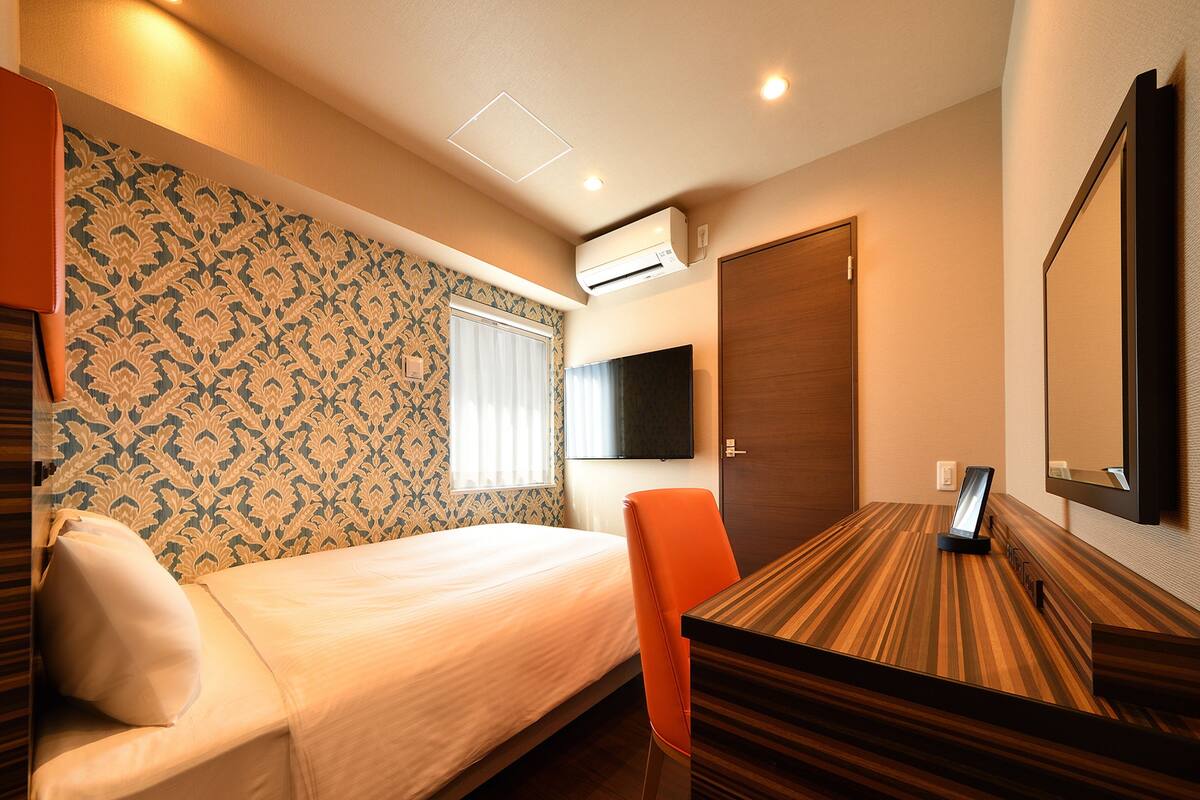 Une chambre d’hôtel équipée d’un lit, d’un bureau, d’une chaise, d’une télévision et d’un appareil de climatisation.