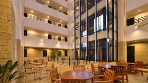 A multi-level indoor space with wooden tables and chairs, large windows, and a stone wall. - Hotel WBF Grande Hakata (Fukuoka)