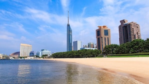 A coastal cityscape with modern buildings, a prominent tower, and a beach. - Hotel WBF Grande Hakata (Fukuoka)
