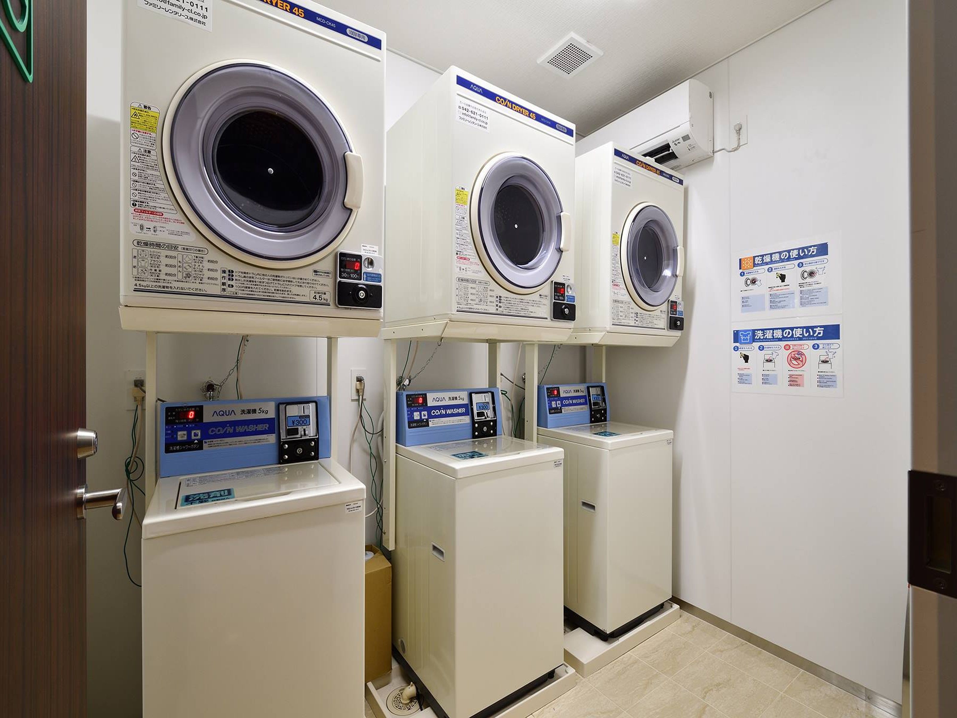 A laundry facility with three front-loading washing machines and two dryers.