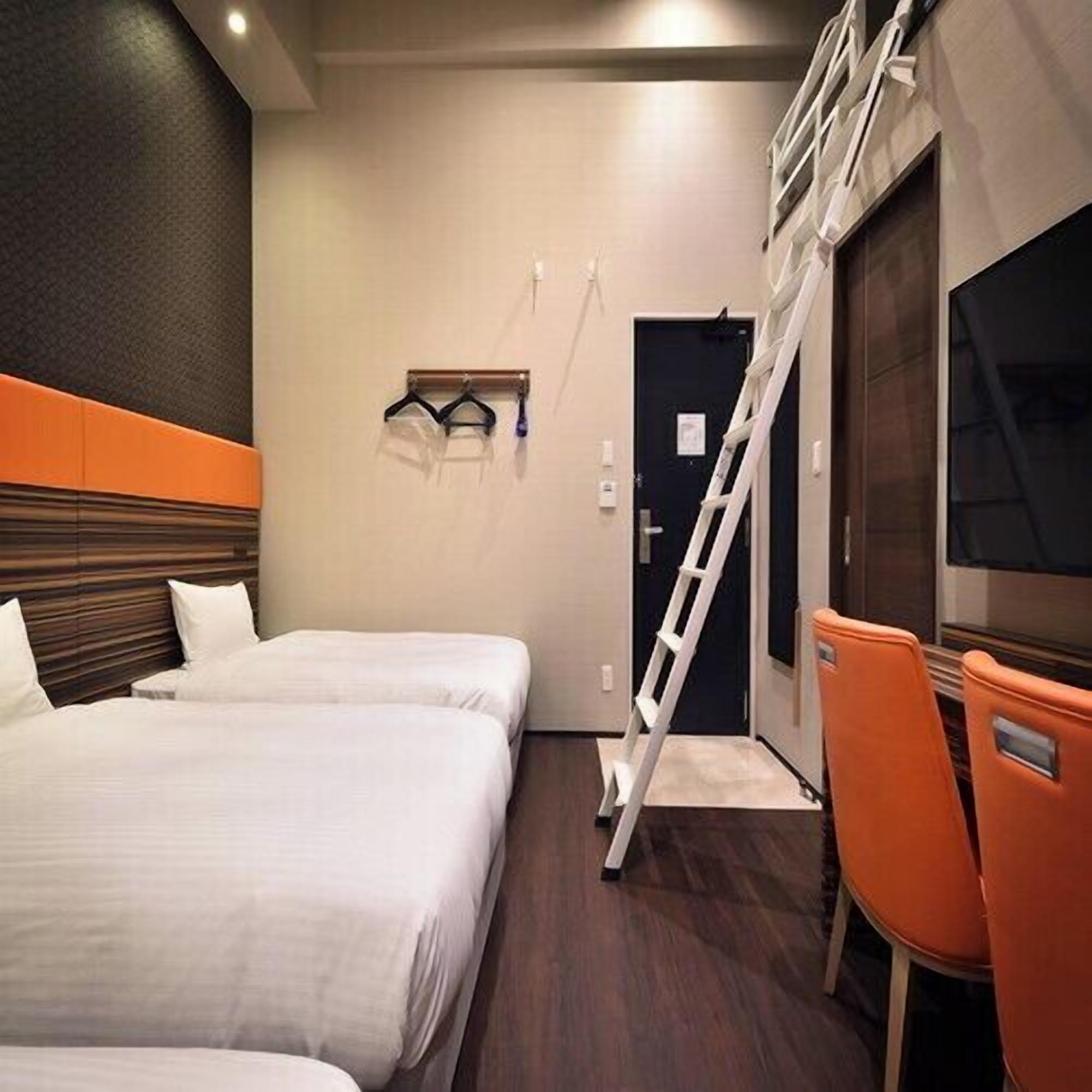 Ein Hotelzimmer mit zwei Betten, einem Schreibtisch, einem Stuhl, einem Fernseher und einer Leiter.