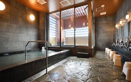 A modern bathroom with a stone floor, a large window, and a row of sinks with mirrors.