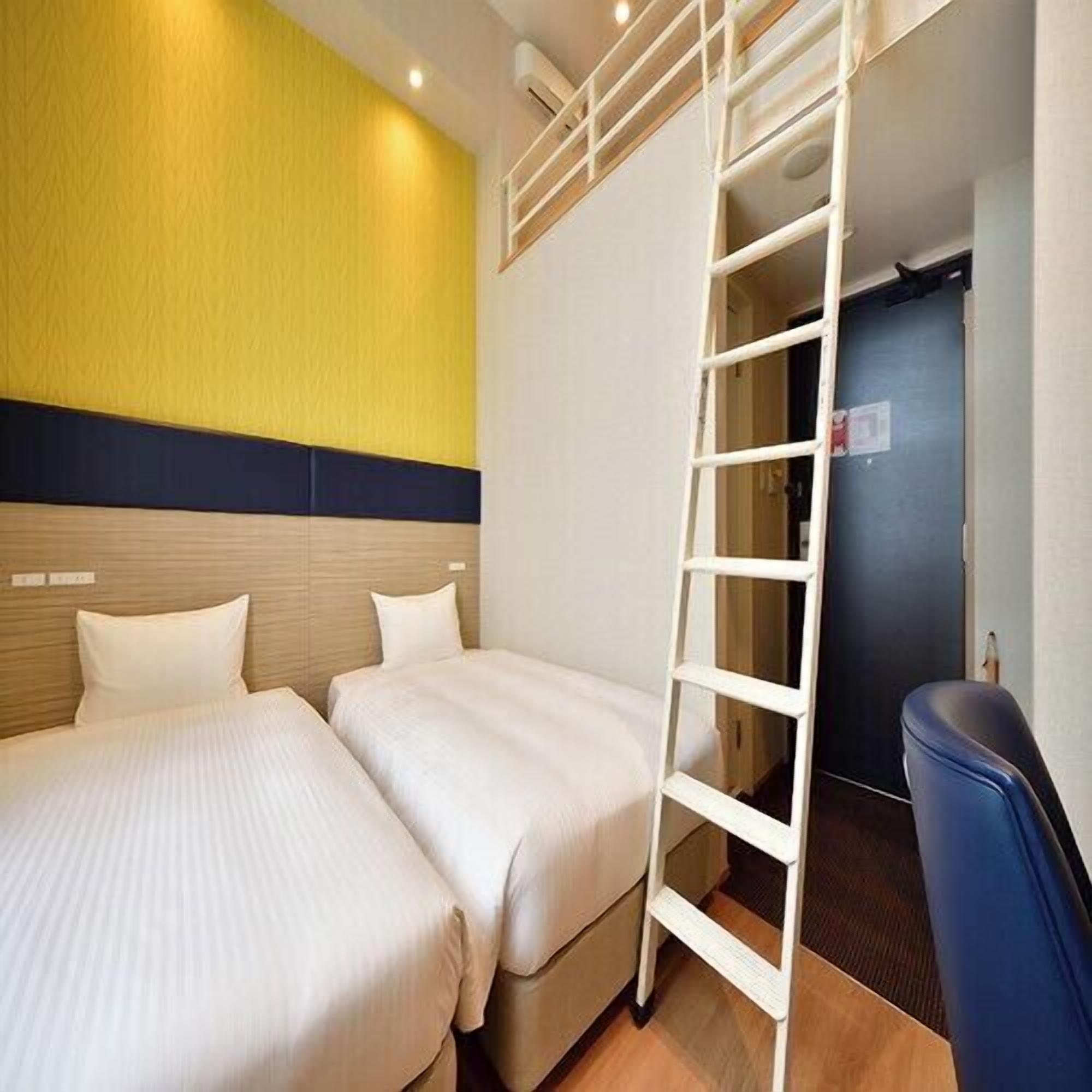 A hotel room with two beds, a wooden headboard, a yellow wall, and a white ladder.