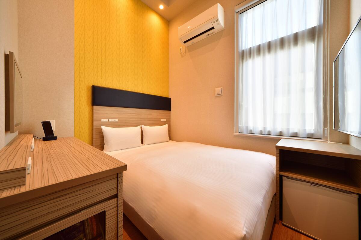 Une chambre d’hôtel équipée d’un lit, de tables de chevet, d’un bureau et d’un appareil de climatisation.