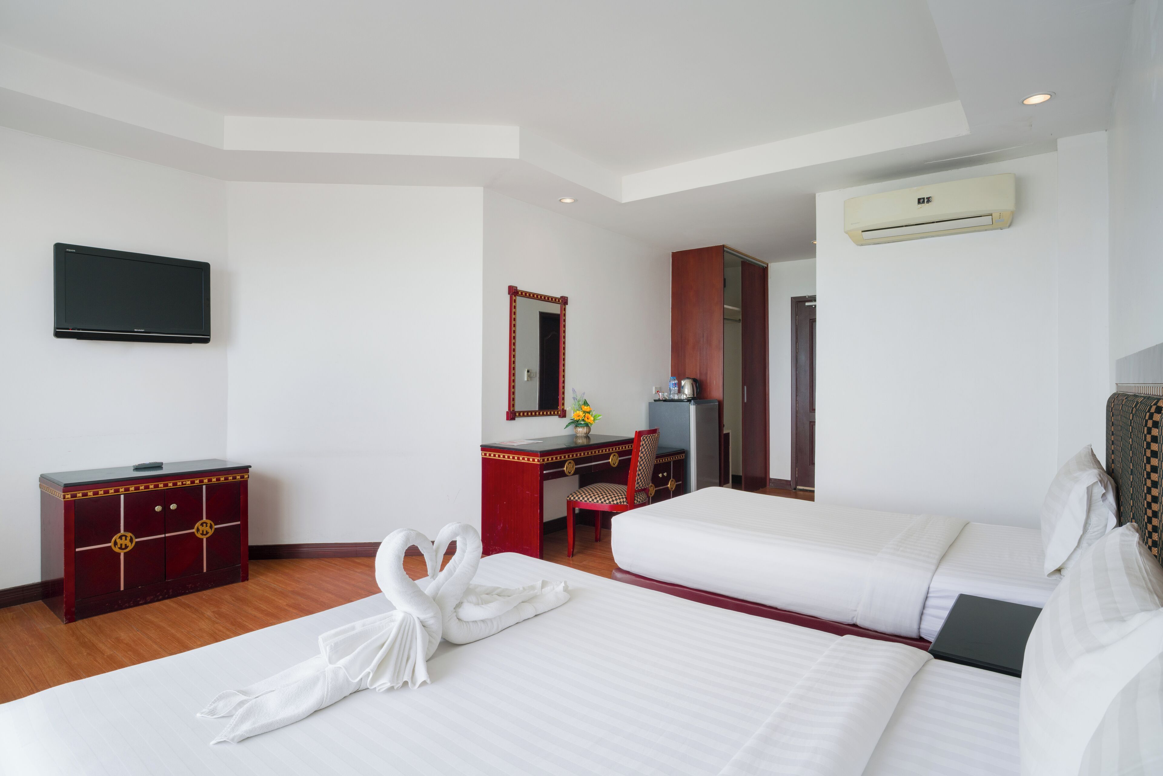 Une chambre d’hôtel avec deux lits, une télévision, un bureau avec une chaise et un appareil de climatisation.