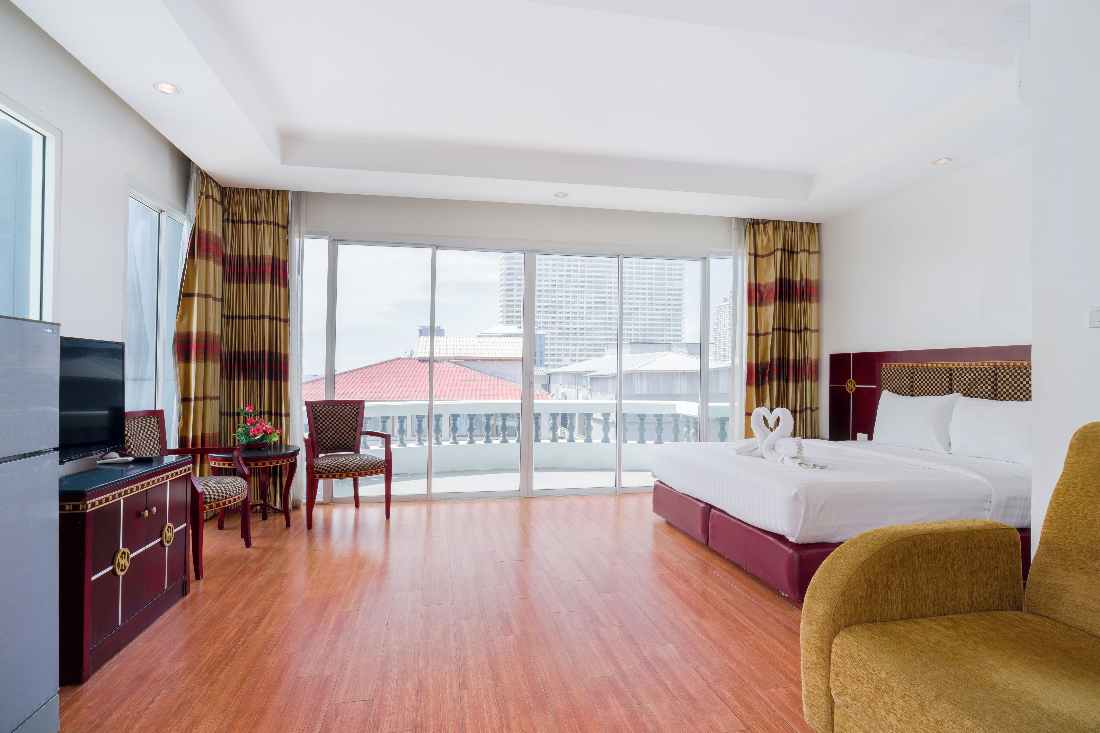 Une chambre d’hôtel avec un grand lit, une télévision, un bureau et un balcon donnant sur les immeubles.