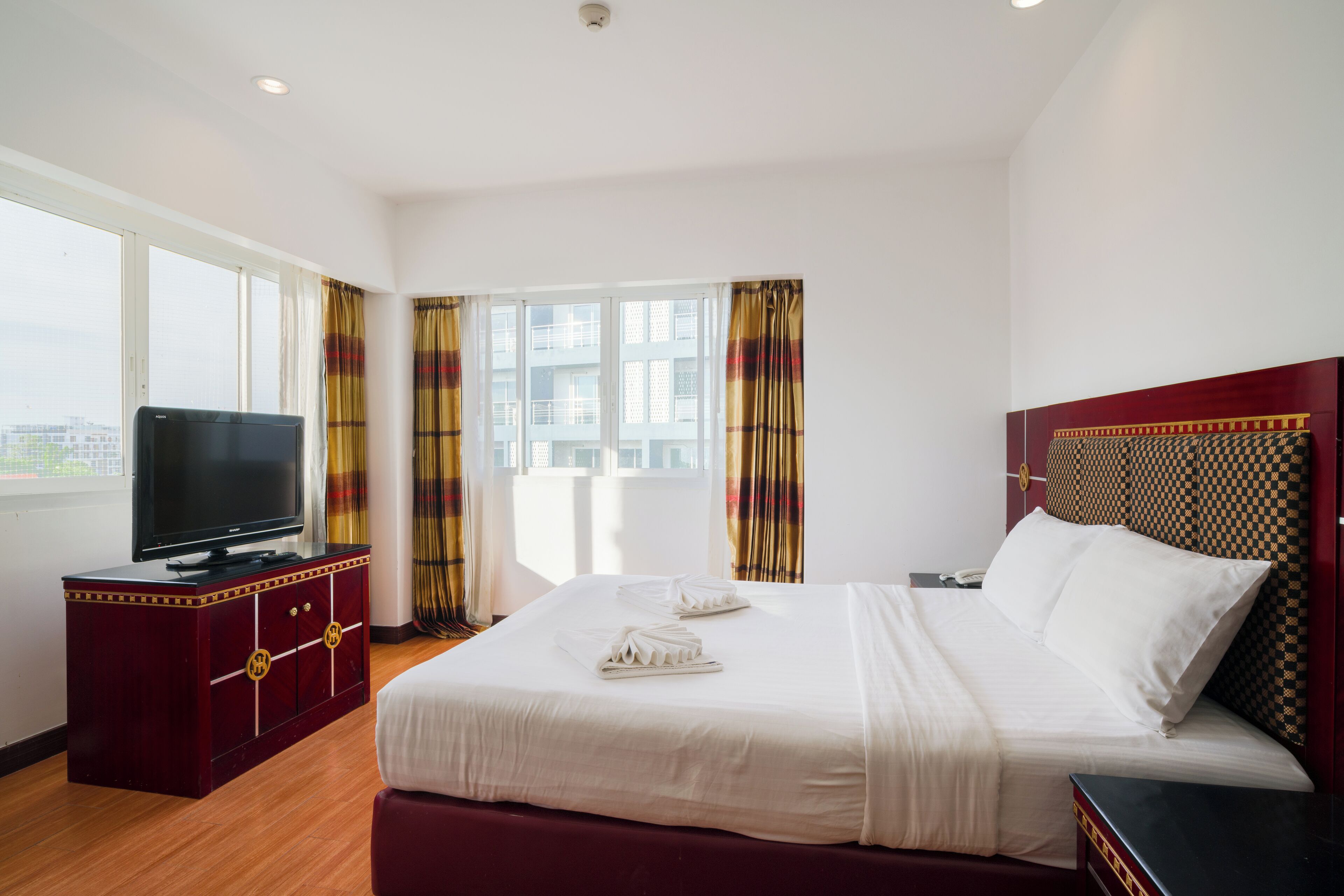 A hotel room with a bed, a TV on a cabinet, and curtains.