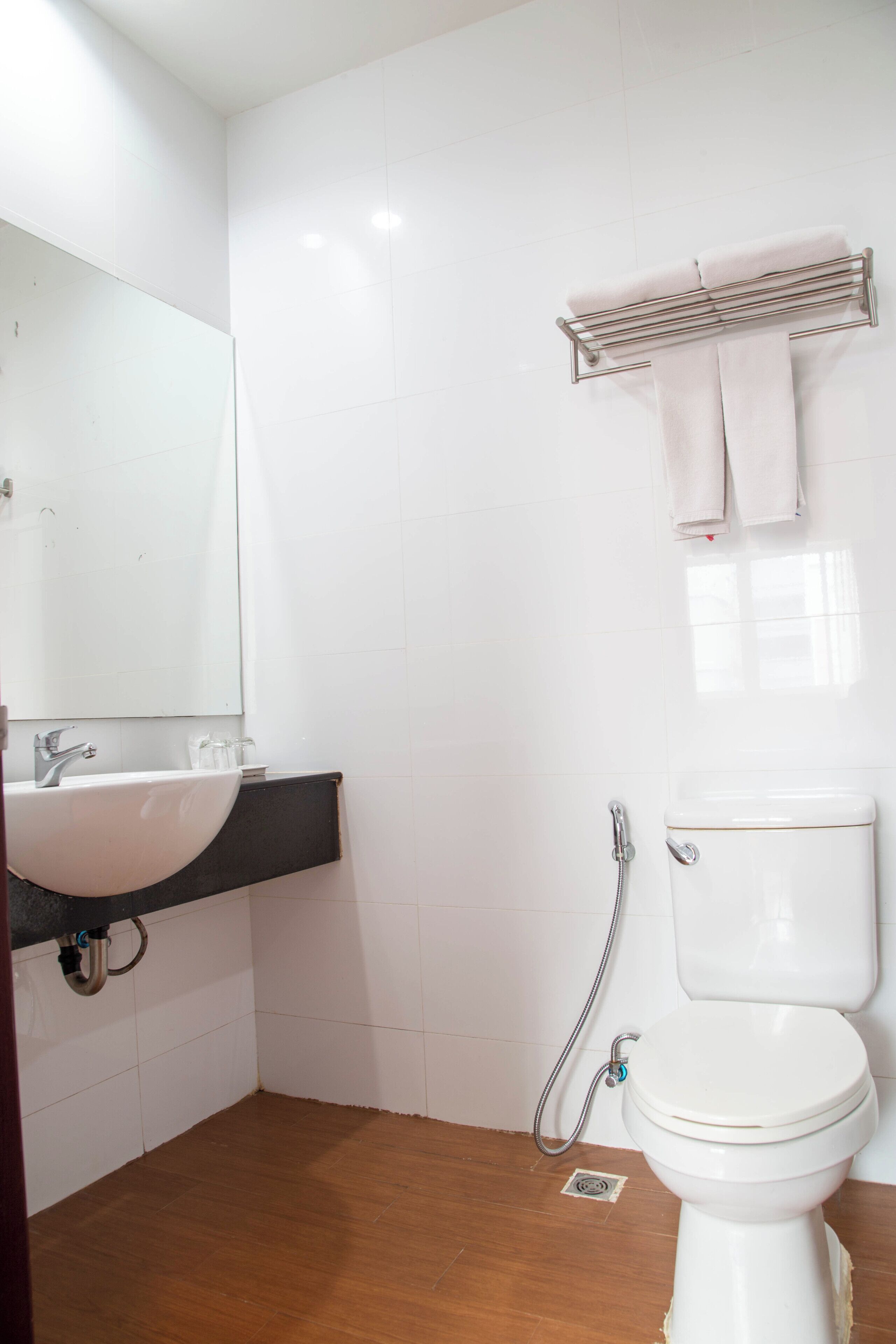 A bathroom with a white sink, a mirror, a toilet, and a towel rack.