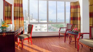 A room with a large window, wooden floor, and red chairs. - Jomtien Hisotel (Pattaya)