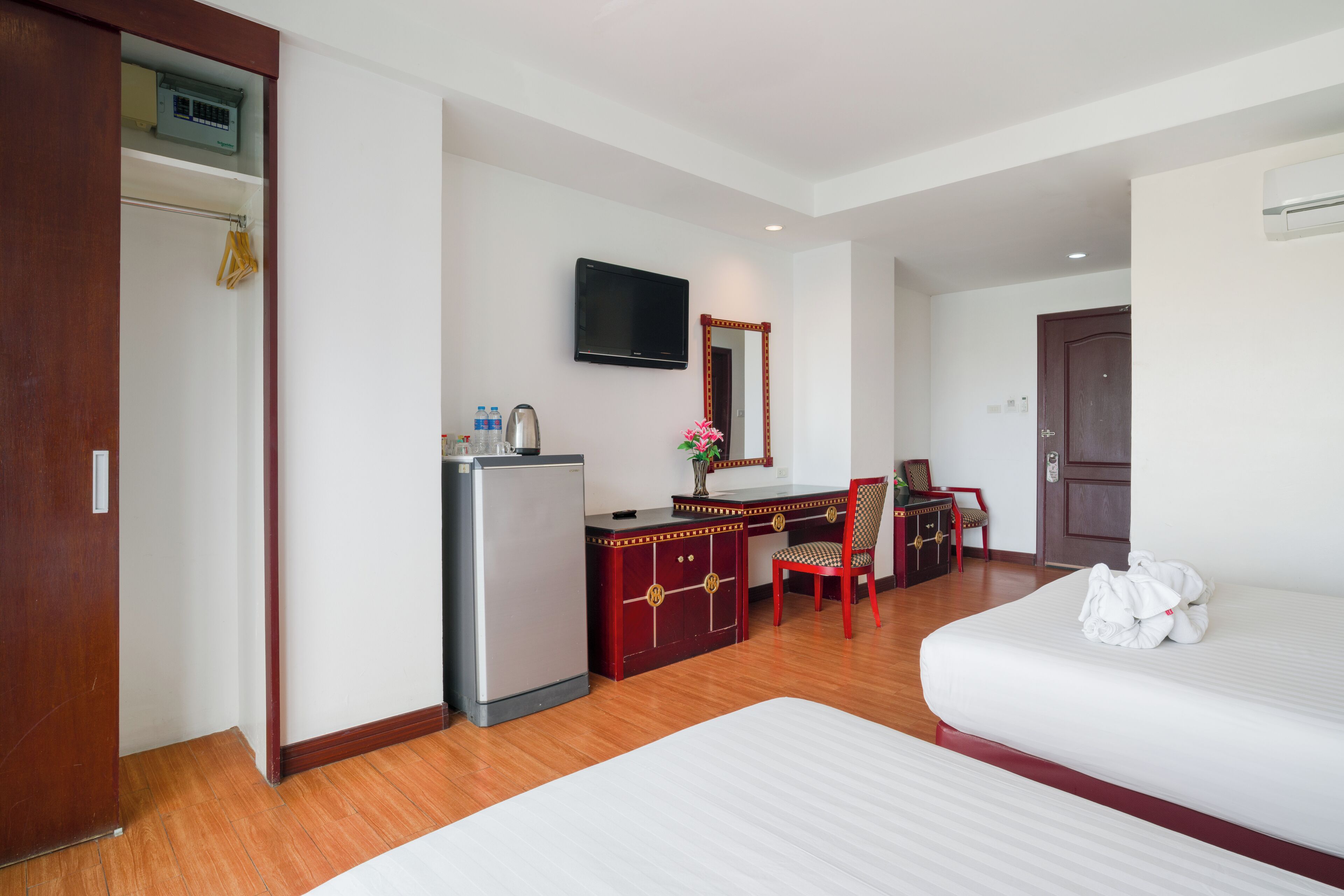 Habitació d'hotel amb un llit, una escriptori amb cadira, un frigorífic, una televisió i un armari.