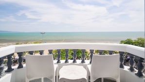 A balcony with two white chairs and a table, overlooking a beach with clear blue water and distant land. - Jomtien Hisotel (Pattaya)
