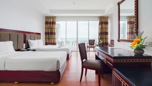 A hotel room with two beds, a desk, a chair, a large mirror, and a view of the sea. - Jomtien Hisotel (Pattaya)