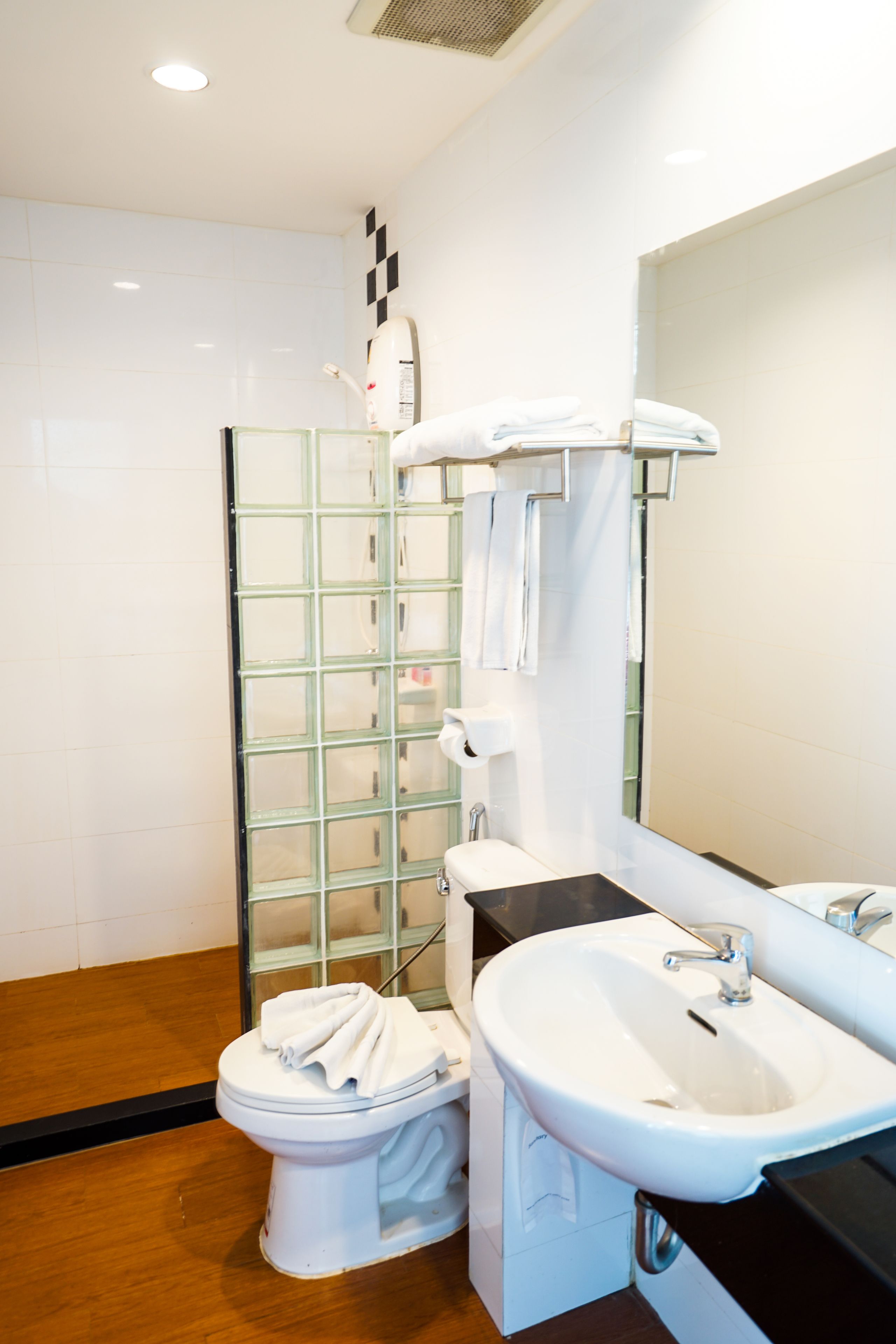 A modern bathroom with a glass shower enclosure, a white toilet, a sink, and a mirror.