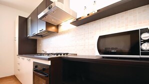 Une cuisine moderne équipée d’une cuisinière à gaz, d’un four, d’un four à micro-ondes et d’une hotte aspirante intégrée.