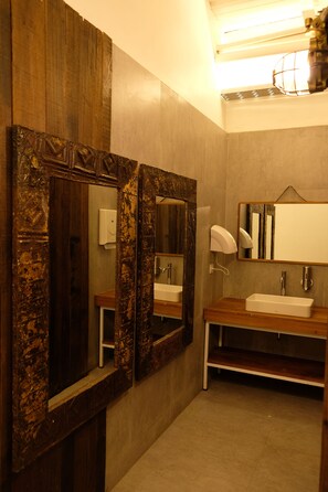 A bathroom with two mirrors, a sink, and a towel dispenser. - M Boutique Hostel Legian (Kuta)
