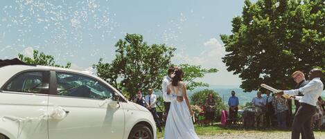 Una ceremonia de boda con un coche blanco e invitados.