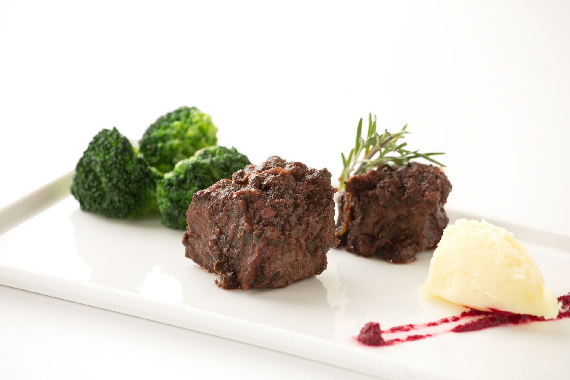 Um prato branco com duas fatias de carne, brócolis e uma porção de purê de batatas.