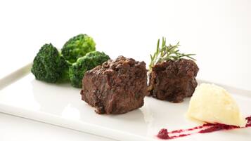 Um prato branco com duas fatias de carne, brócolis e uma porção de purê de batatas.