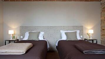 Quarto duplo com duas camas, cada uma com cabeceira, mesas de cabeceira e luminárias, e uma parede de tijolos.