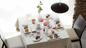 Una mesa preparada para una comida, con platos de comida, vasos y cubiertos.