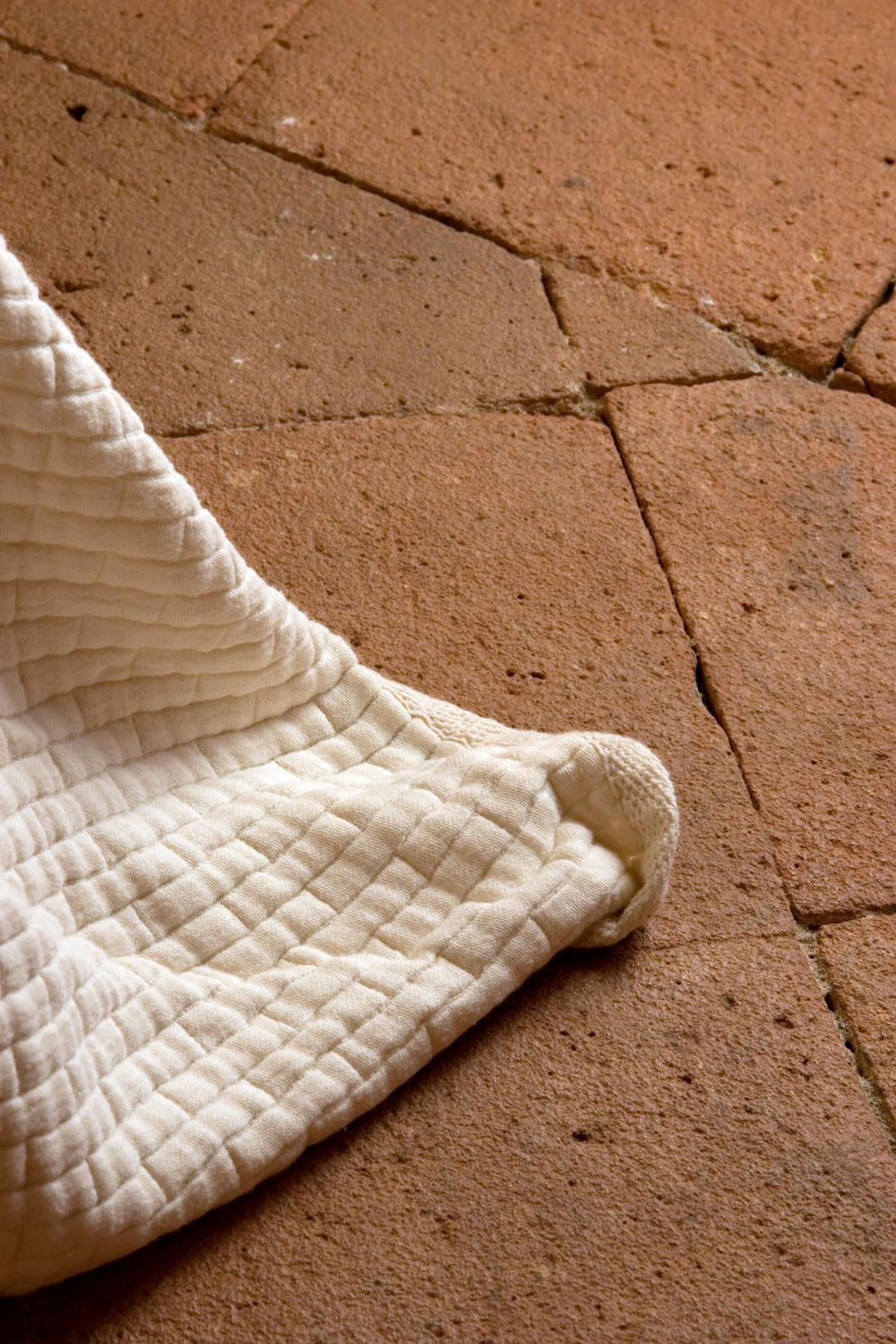 A quilted blanket on a brick floor.