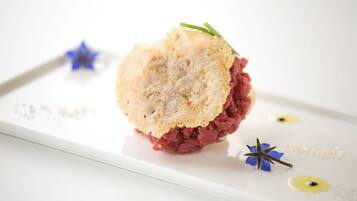 Un postre con una cobertura similar a pan, sobre un plato blanco, decorado con una ramita de flores verdes y azules.