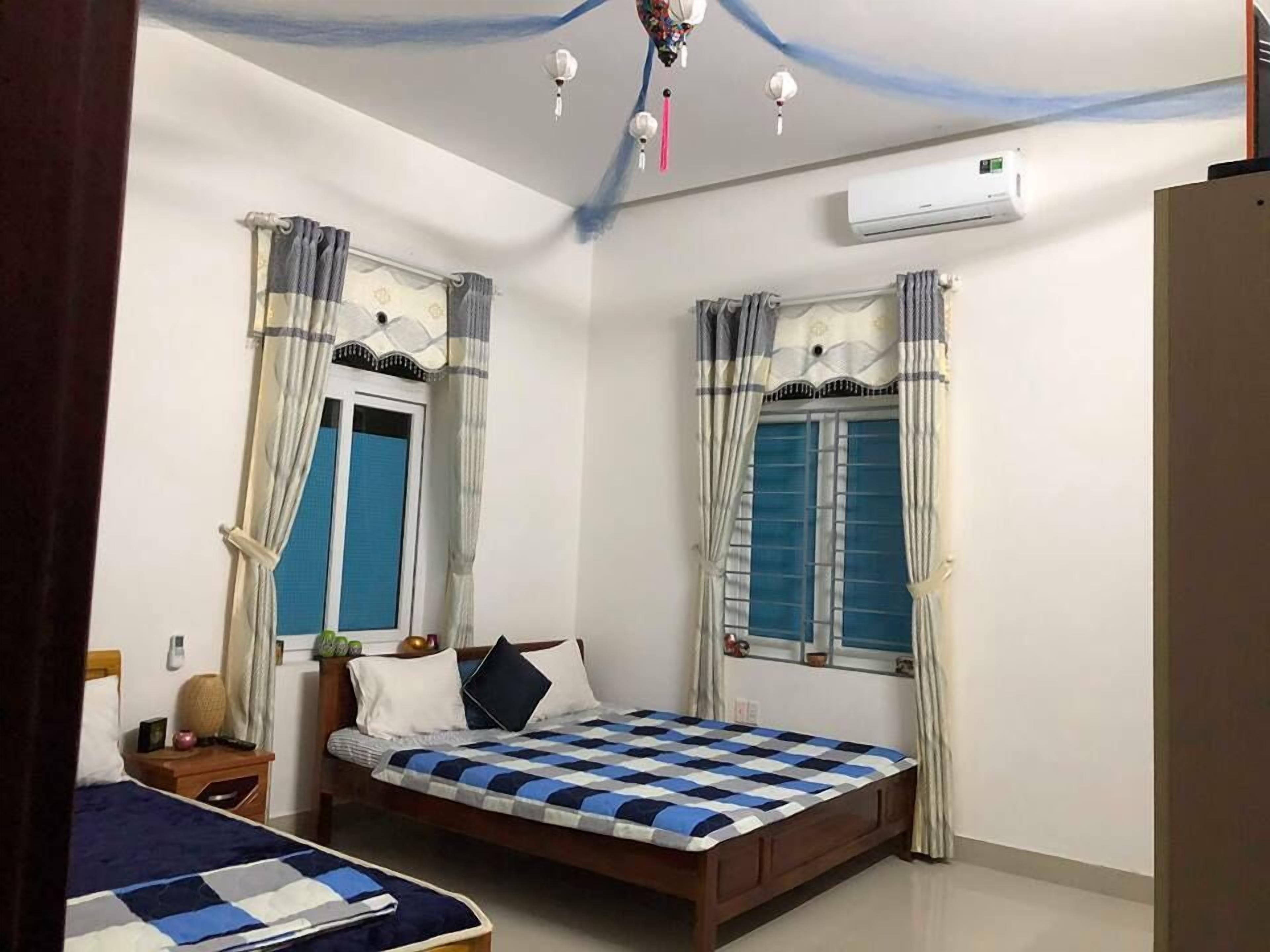 A bedroom with two beds, a window, a nightstand, and an air conditioning unit.