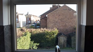 A window with a view of a residential area, including houses and a small wooden structure. - Toothbrush Apartments - Ipswich East - Cauldwell Ave (Ipswich)