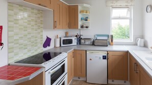 A compact kitchen with wooden cabinets, a microwave, a toaster, and a dishwasher. - Toothbrush Apartments - Ipswich East - Cauldwell Ave (Ipswich)