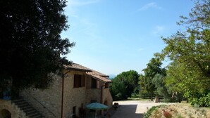 A stone building with a tiled roof, a staircase, and a patio area with outdoor seating. - Agriturismo Il Borghetto (Todi)