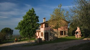 A rustic stone house with a chimney, surrounded by trees and a gravel path. - Agriturismo Il Borghetto (Todi)