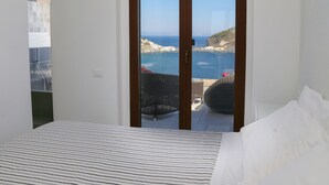 A bedroom with a bed, a view of the sea, and a balcony with wicker furniture. - Torre Sant'Angelo (Forio)