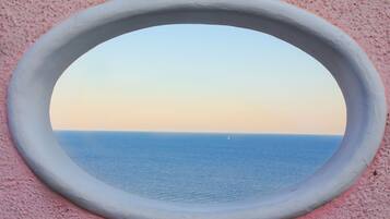 Een rond raam met uitzicht op zee en een heldere lucht.