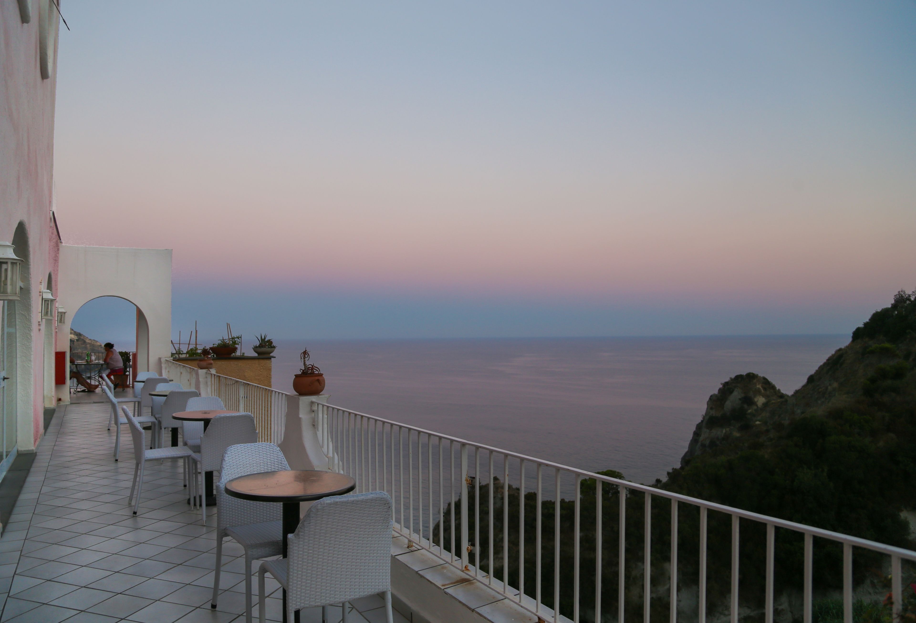 A terrace with outdoor seating and a view of the sea.