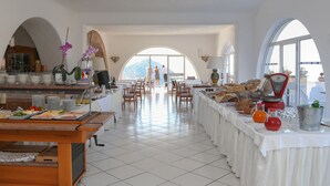 A spacious dining area with a buffet setup, arched windows, and a view of the mountains. - Torre Sant'Angelo (Forio)